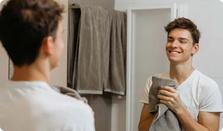 guy smiling into reflection of himself holding towel